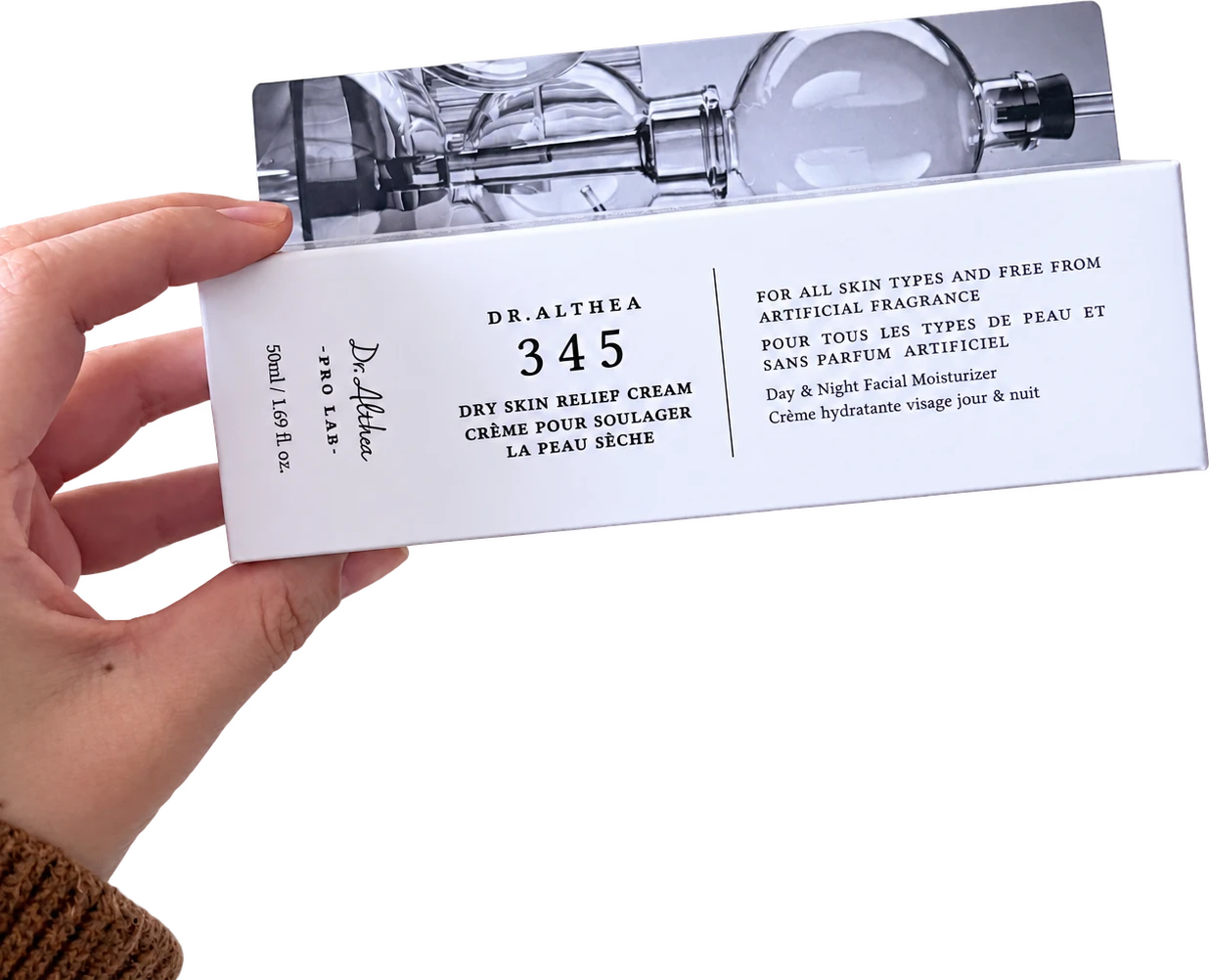 Dr. Althea 345 carton held horizontally, with its front label and opened flap showing laboratory glassware.