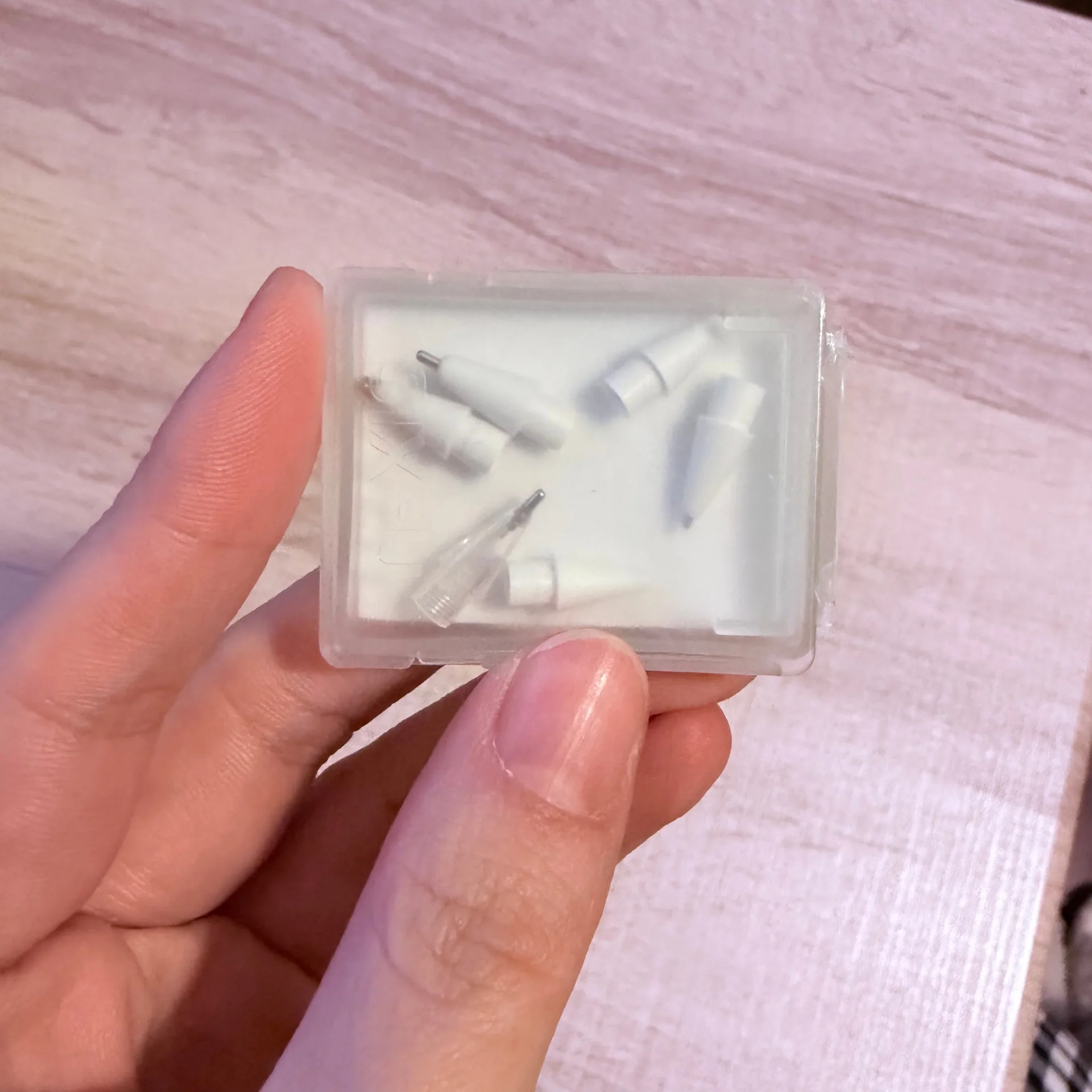 A hand holding a translucent case containing replacement Pencil nibs with different tip shapes.
